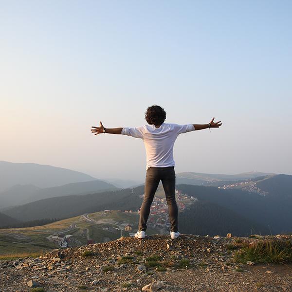 A man standing on the edge of cliff with his arms open